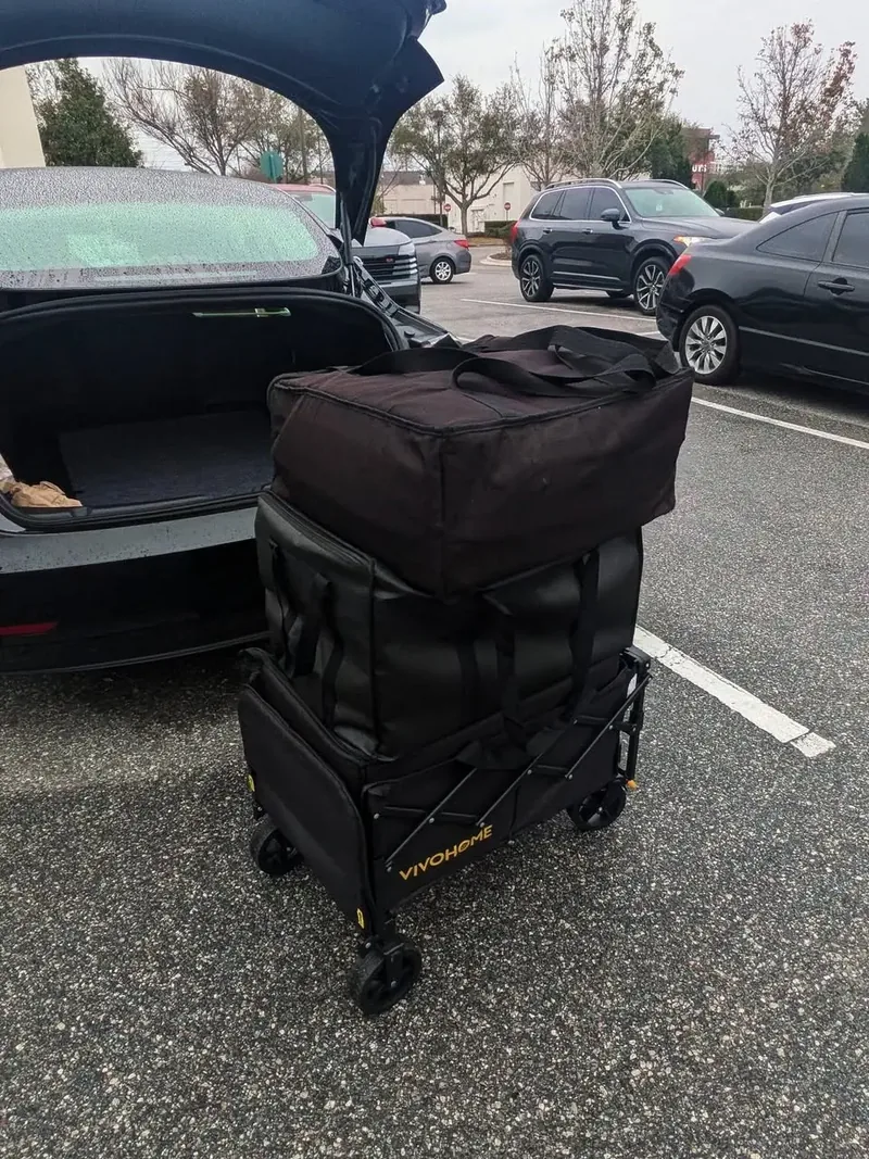 An insulated catering delivery cart staged beside a vehicle for transport
